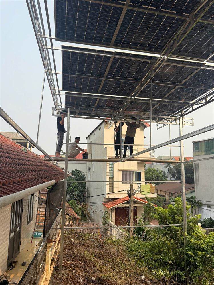 Đội thi công dựng khung giàn nâng cao đỡ tấm pin phía trên mái nhà